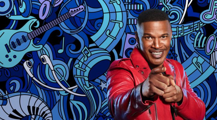 actor and host jamie foxx wearing a red leather jacket and smiling at the audience
