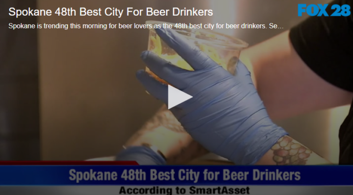 an employee with gloves holding a plastic cup of beer