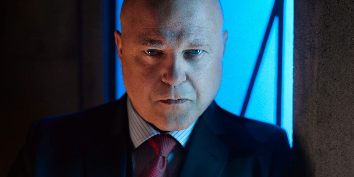 actor michael chicklis in image from fox series gotham, wearing a dark suit with a striped shirt and red tie and a grim expression on his face